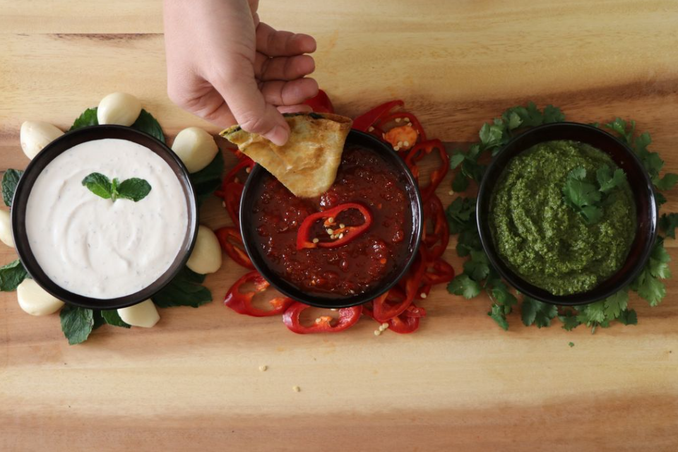 Several chutneys laying across a cutting board.